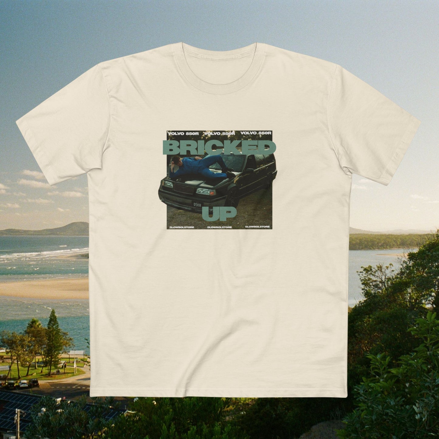 Beige t-shirt with a graphic of a rollercoaster and text 'BRICKED UP' on a scenic background.
